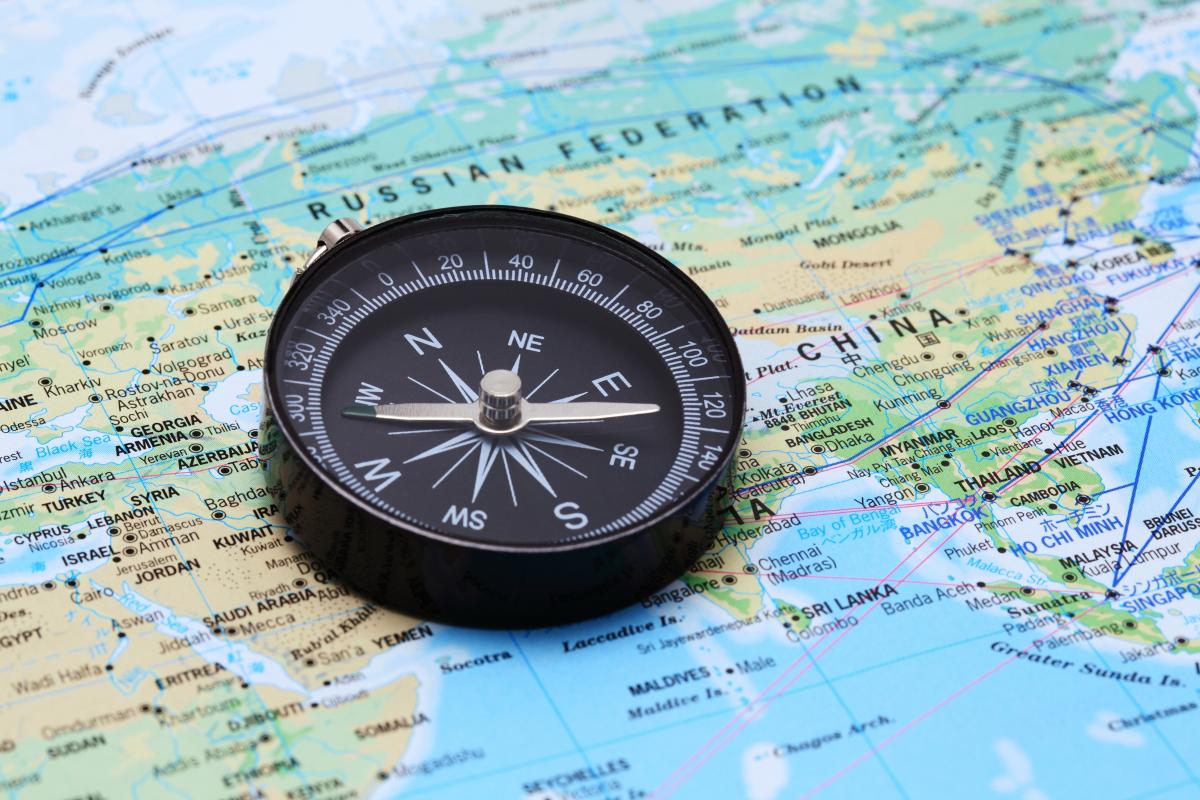 A compass resting on a world map spanning the Middle East and Asia, symbolising strategic capital allocation across the Gulf region.